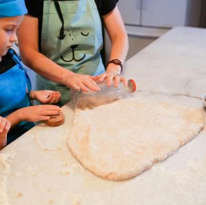 Children and parent making cookies together in a cozy kitchen setting, fostering family bonding time.